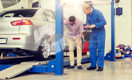 Image of auto mechanic with clipboard and man at car shop