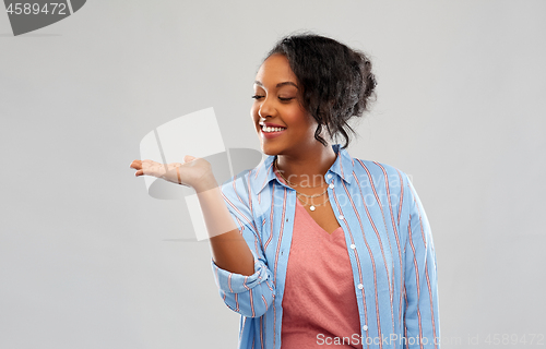 Image of happy african woman holding something on hand