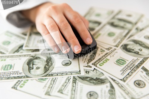 Image of close up of hand with computer mouse on money