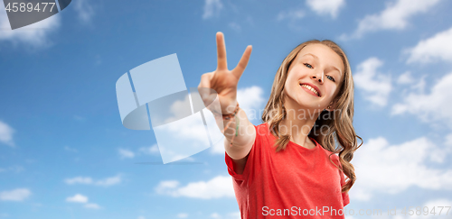 Image of smiling teenage girl showing peace over sky