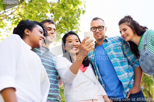 Image of happy friends with smartphone at summer park