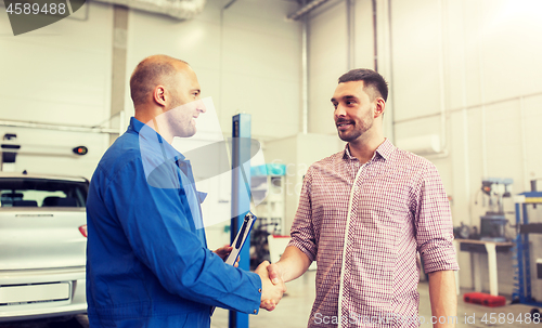 Image of auto mechanic and man shaking hands at car shop