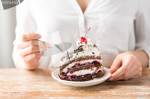 Image of woman eating piece of layer cake with cherry