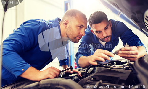 Image of mechanic men with wrench repairing car at workshop