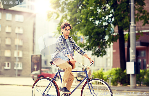 Image of young hipster man with bag riding fixed gear bike