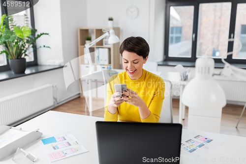 Image of smiling ui designer using smartphone at office