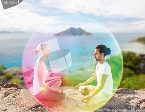 Image of couple doing yoga in lotus pose with rainbow aura