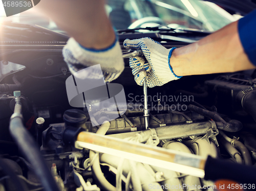 Image of mechanic man with wrench repairing car at workshop