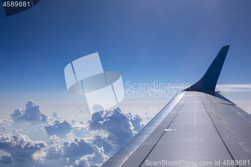 Image of Plane wing on a blue sky cloudy background