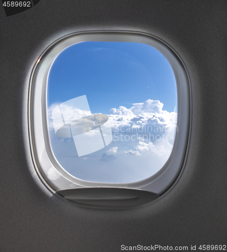 Image of View of cloudy blue clear sky through airplane porthole.