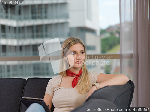 Image of young woman on sofa at home surfing web