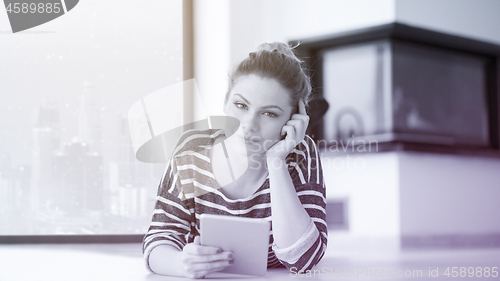 Image of woman using tablet computer in front of fireplace