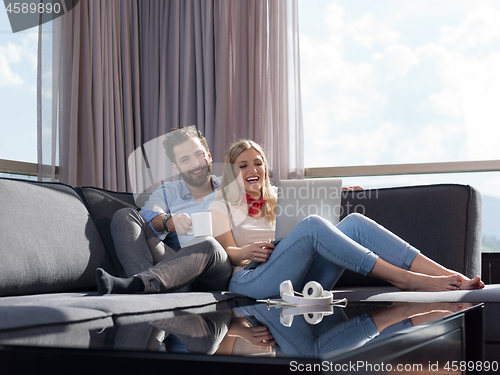 Image of couple relaxing at  home using laptop computer