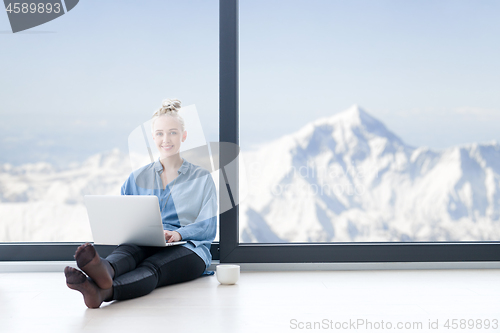 Image of woman drinking coffee and using laptop at home