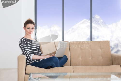 Image of young woman on sofa at home websurfing