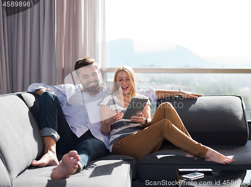 Image of couple relaxing at  home with tablet computers