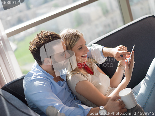 Image of couple relaxing at  home with tablet computers