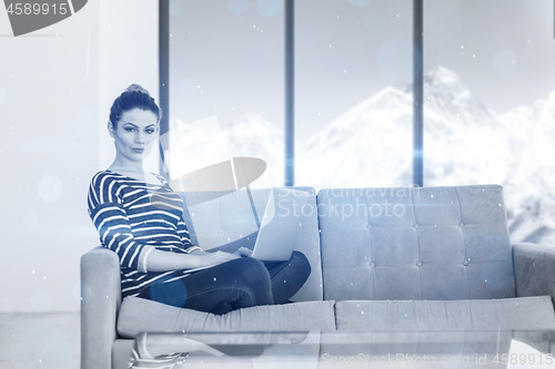 Image of young woman on sofa at home websurfing