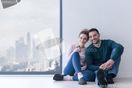 Image of young couple sitting on the floor near window at home