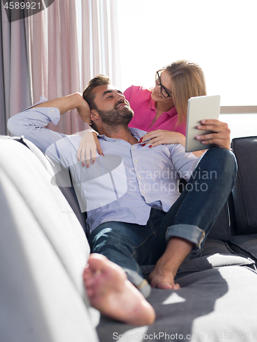 Image of couple relaxing at  home with tablet computers