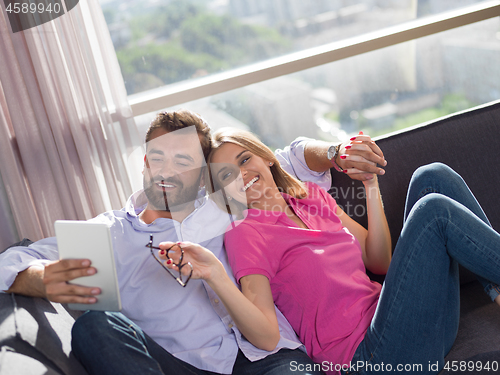 Image of couple relaxing at  home with tablet computers