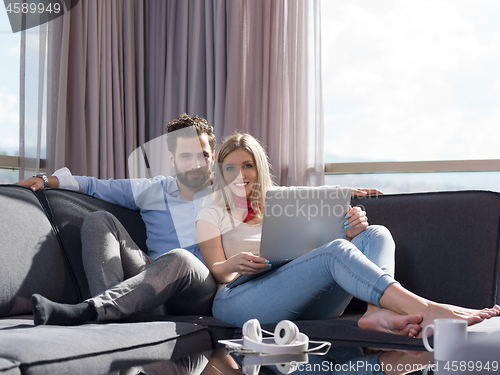 Image of couple relaxing at  home using laptop computer