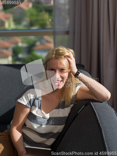 Image of young woman on sofa at home surfing web