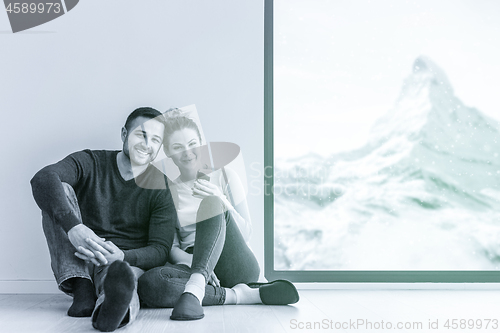 Image of young couple sitting on the floor near window at home