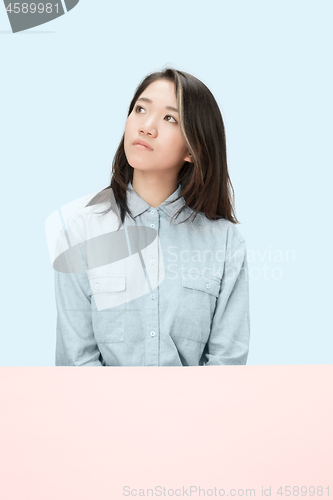 Image of The serious business woman sitting and looking up against blue background.