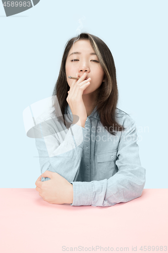 Image of Handsome young women smoking cigar while sitting at table with newspaper in sunglasses