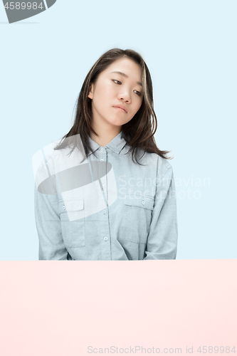 Image of The serious business woman sitting and looking down against blue background.