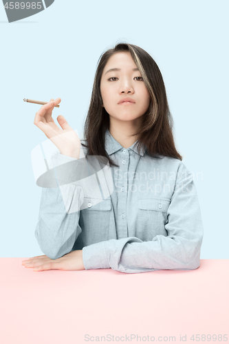 Image of Handsome young women smoking cigar while sitting at table with newspaper in sunglasses