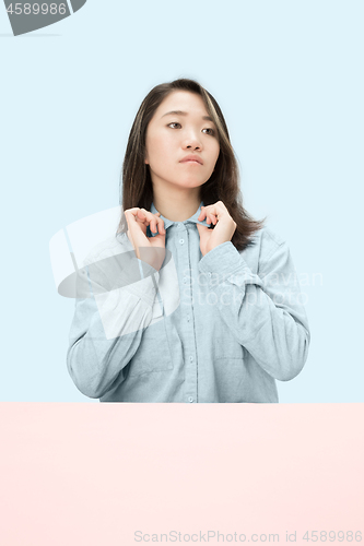 Image of The serious business woman sitting and looking at left against blue background.