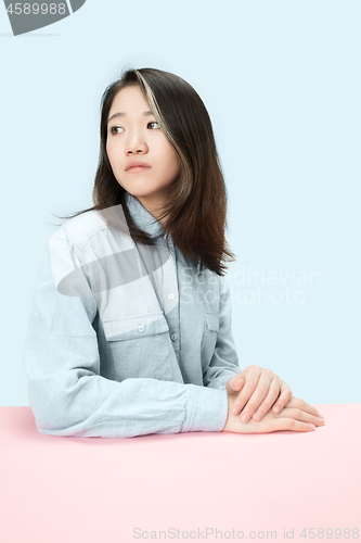 Image of The serious business woman sitting and looking at left against blue background.