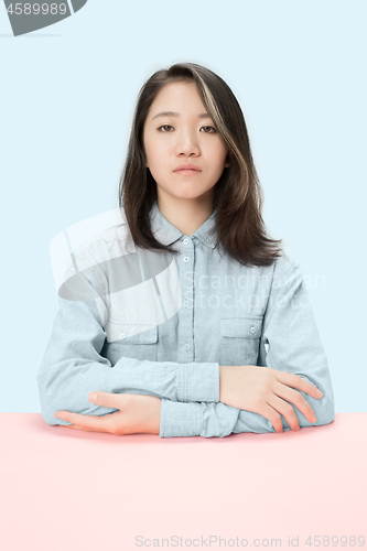 Image of The serious business woman sitting and looking at camera against blue background.