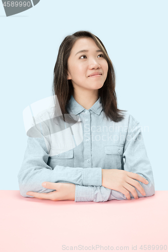 Image of The serious business woman sitting and looking up against blue background.