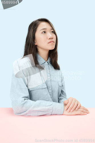 Image of The serious business woman sitting and looking up against blue background.