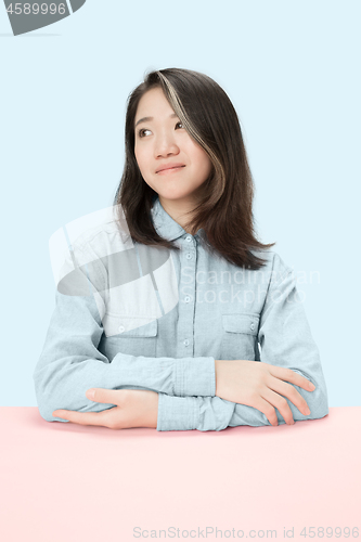 Image of The serious business woman sitting and looking at left against blue background.