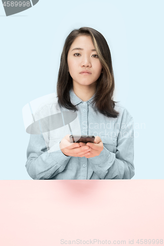 Image of The serious business woman sitting and looking at camera against blue background.