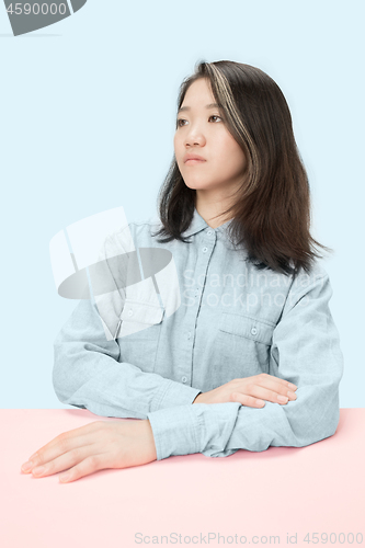 Image of The serious business woman sitting and looking at left against blue background.