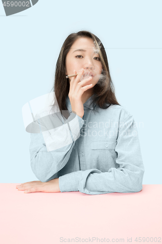 Image of Handsome young women smoking cigar while sitting at table with newspaper in sunglasses