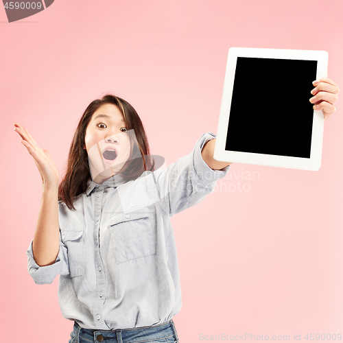 Image of Portrait of a confident casual girl showing blank screen of laptop isolated over pink background