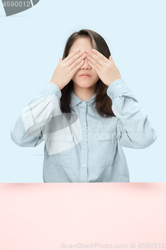 Image of Young woman sitting at table at studio with eyes closed isolated on blue