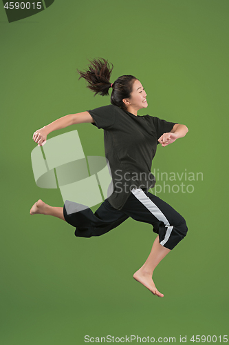 Image of Freedom in moving. Pretty young woman jumping against green background