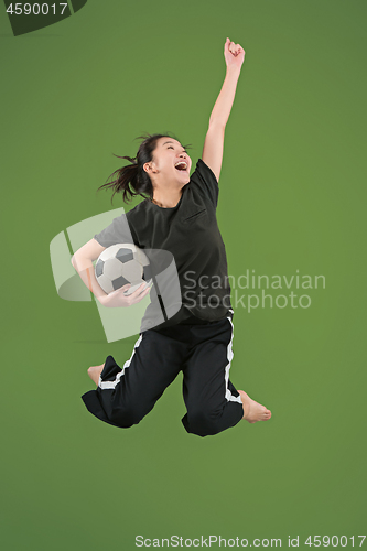 Image of Forward to the victory.The young woman as soccer football player jumping and kicking the ball at studio on green