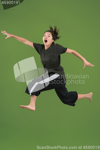 Image of Freedom in moving. Pretty young woman jumping against green background