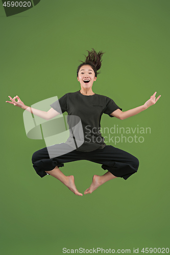 Image of Freedom in moving. Pretty young woman jumping against green background