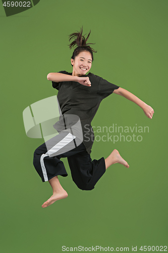 Image of Freedom in moving. Pretty young woman jumping against green background