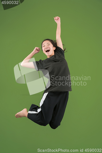 Image of Freedom in moving. Pretty young woman jumping against green background