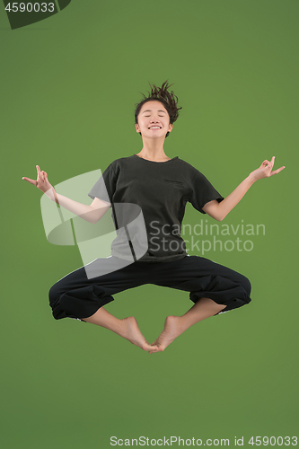 Image of Freedom in moving. Pretty young woman jumping against green background